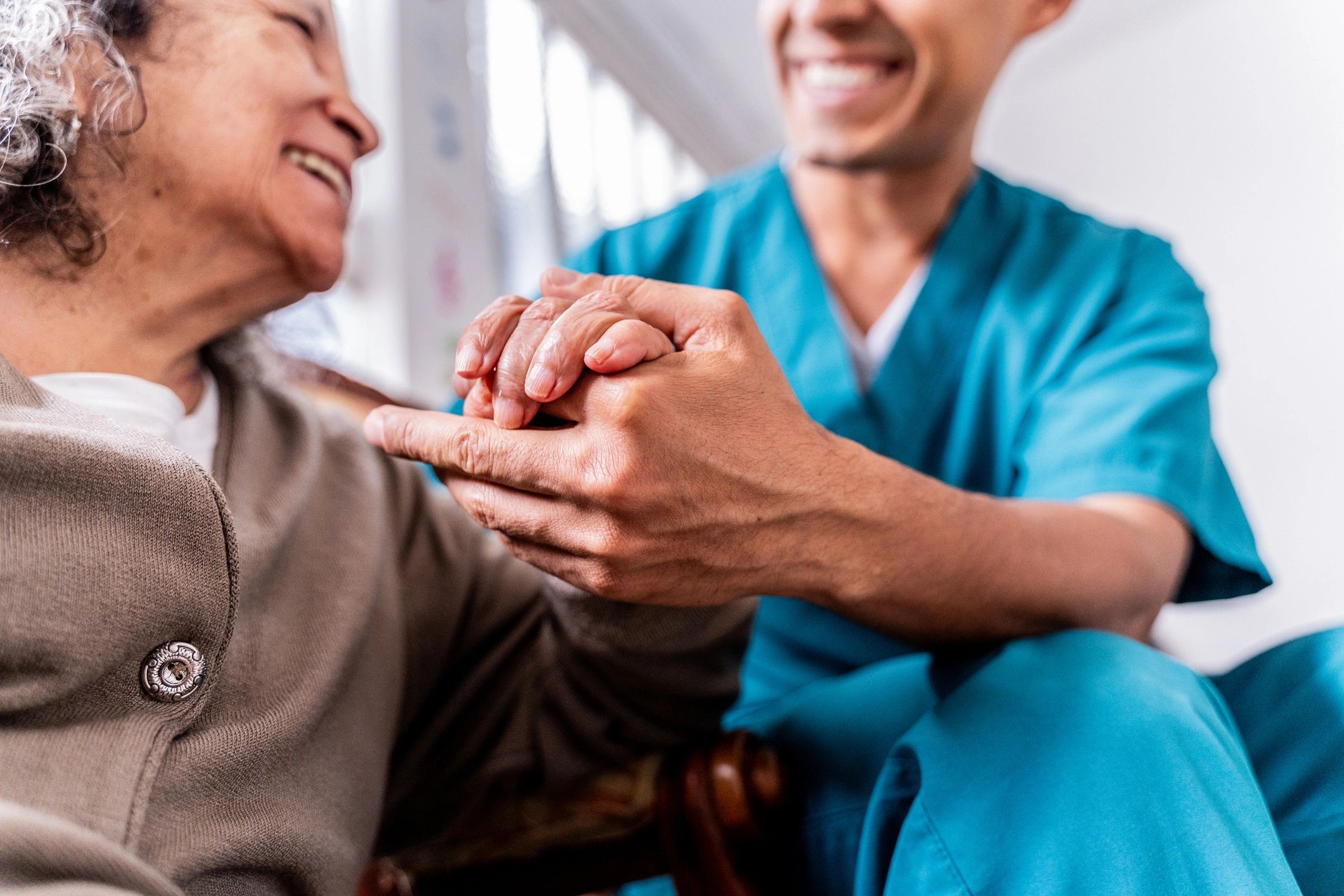 Caregiver holding hands with a senior woman at home