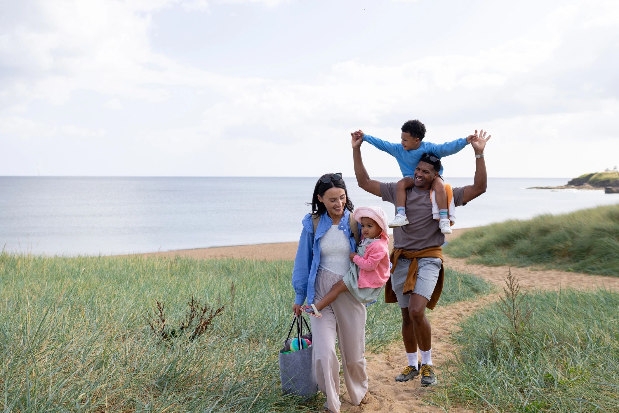 Family walking along a sandy path near the beach