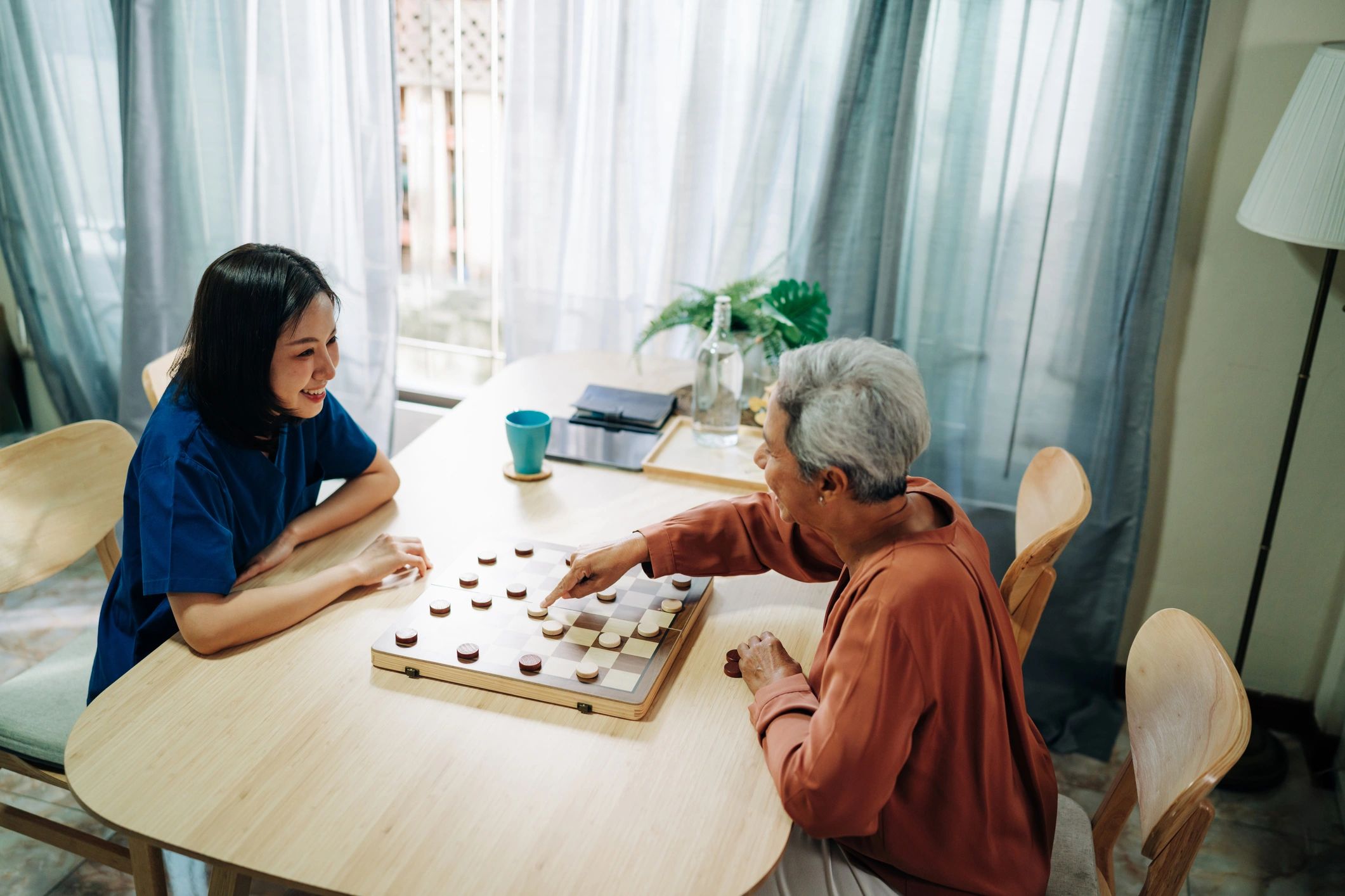 Caregiver and senior playing a board game at home